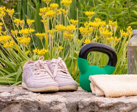 a pair of shoes sitting on top of a rock next to a garden