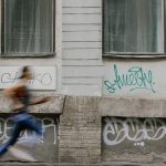 Blurred motion of a woman running past a graffiti-covered urban wall. Captures dynamic energy.