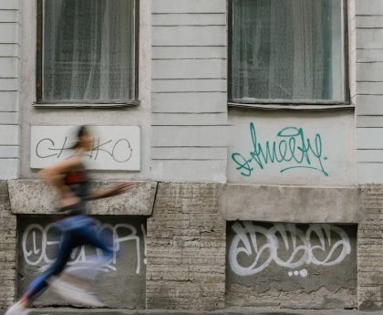 Blurred motion of a woman running past a graffiti-covered urban wall. Captures dynamic energy.